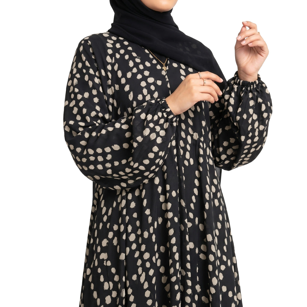 Pebble Muse Abaya with a black base, beige scattered spot print, and flowing full-length silhouette with front open 