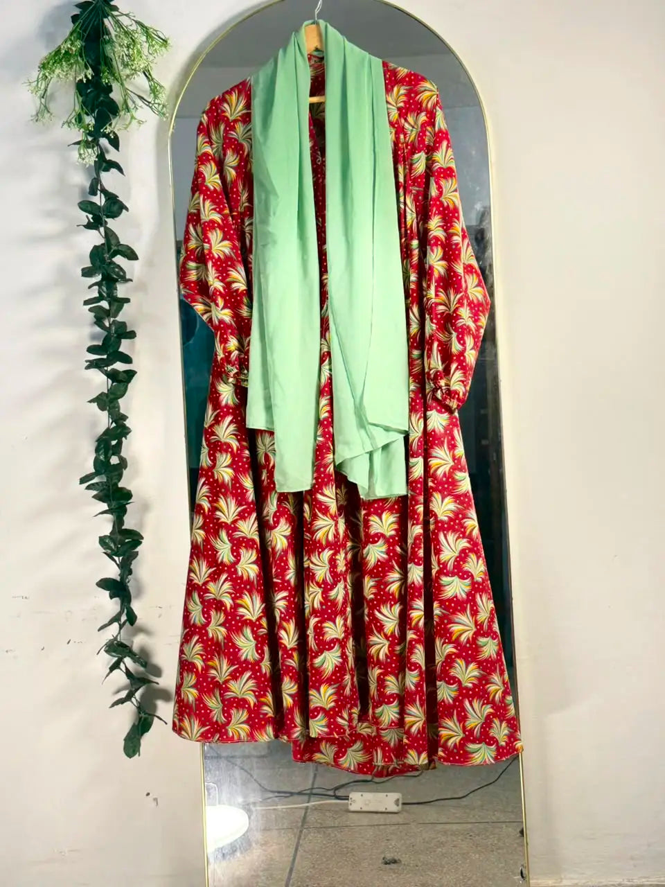 Petal Whirl Abaya featuring a red base, swirling green and cream motifs, and a full-length silhouette with open front